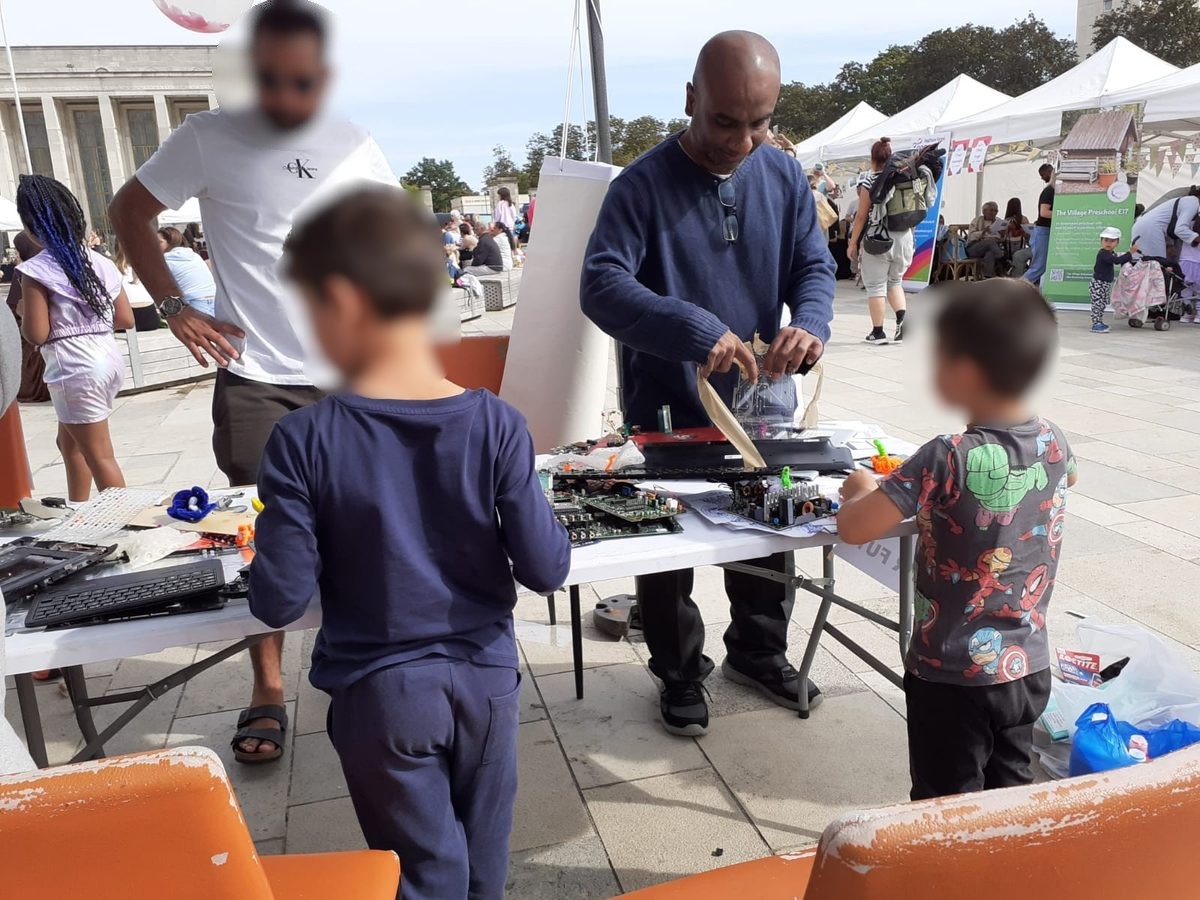 Children and adults taking apart electronics together at a community repair workshop